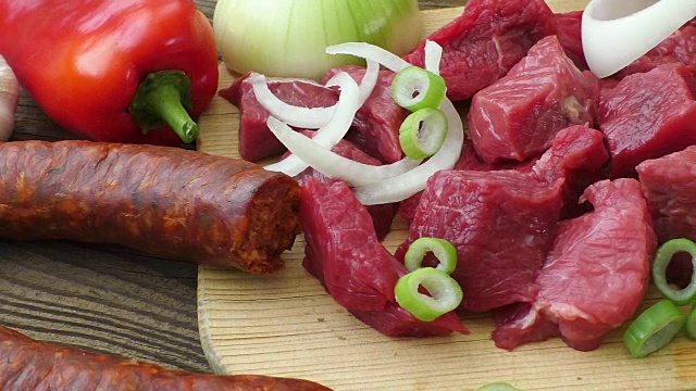 炖菜、炖牛肉或汤的原料新鲜的生牛肉剁碎放在木砧板上，配上香料和蔬菜。视频素材