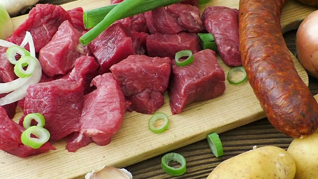 炖菜、炖牛肉或汤的原料新鲜的生牛肉剁碎放在木砧板上，配上香料和蔬菜。视频素材
