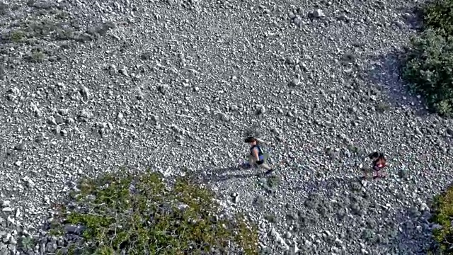 在一个阳光明媚的日子里，两名跑步者在一座岩石山上跑步视频素材