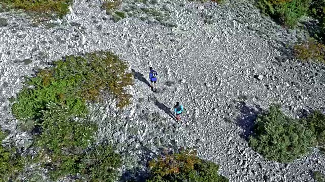 空中情侣在一个阳光明媚的日子里在地中海的一座岩石山上跑步视频素材