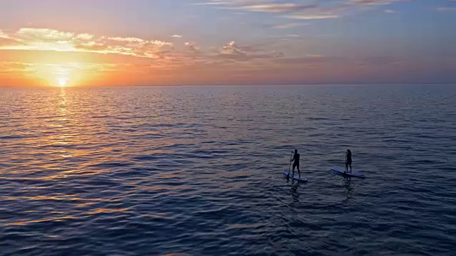 在亚得里亚海美丽的日落中，两个人划着他们的sup视频下载