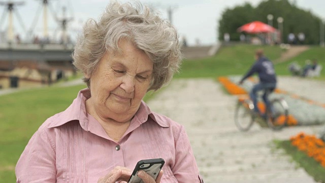 微笑的成熟的老妇人拿着智能手机视频素材