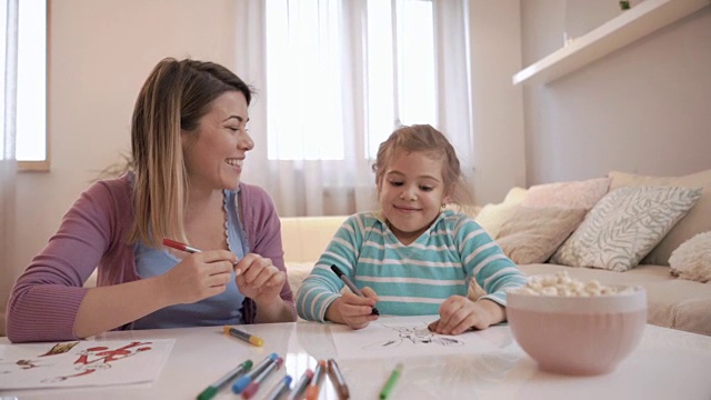 有创意的小女孩在纸上画画，和她的母亲交流。视频素材