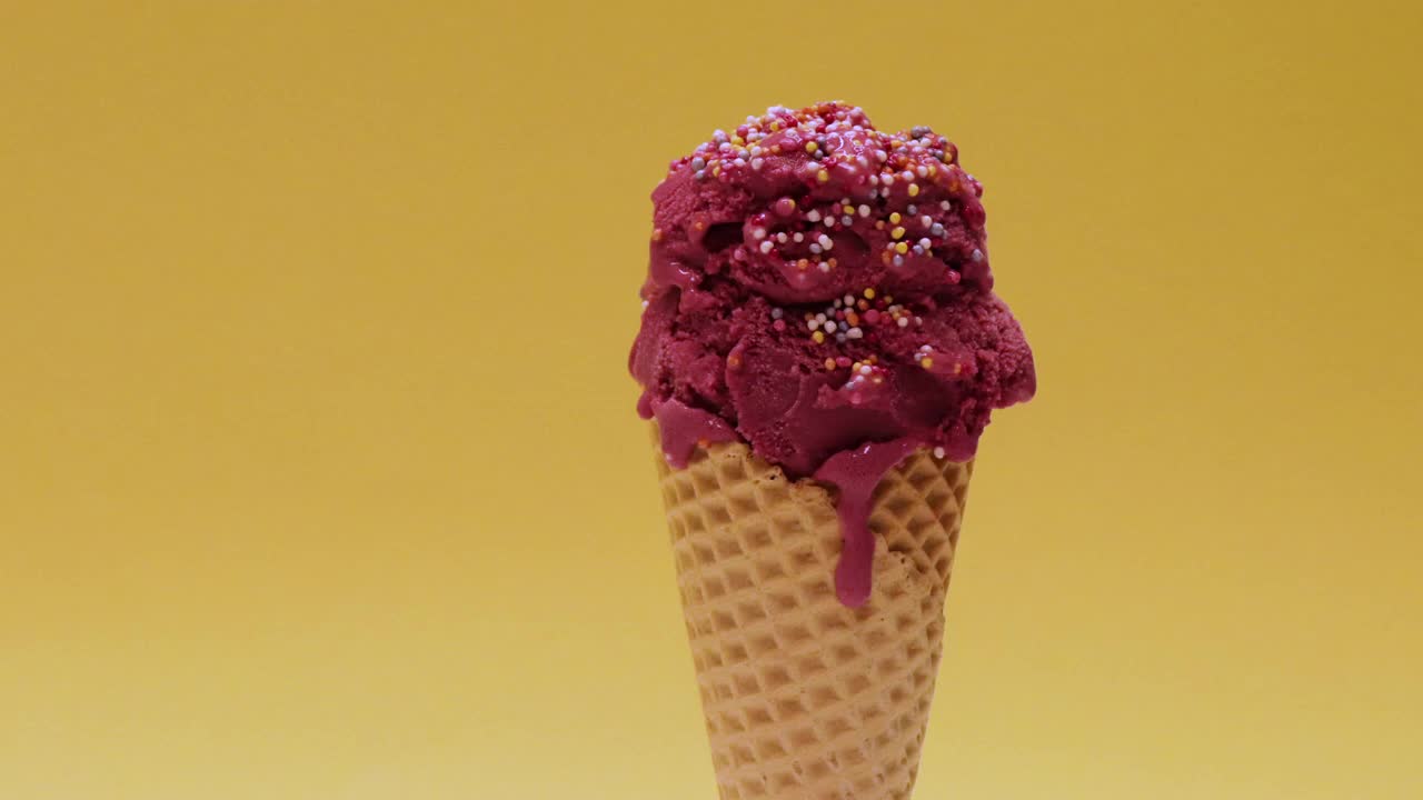 暗粉色的冰淇淋，在黄色的背景下慢慢融化视频下载