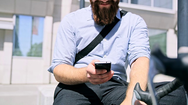 一名蓄着胡须的男子在办公大楼前使用智能手机视频素材