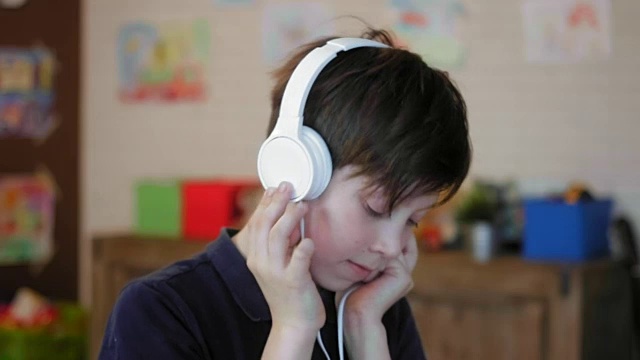 一个可爱的小男孩戴着耳机听音乐的肖像视频素材