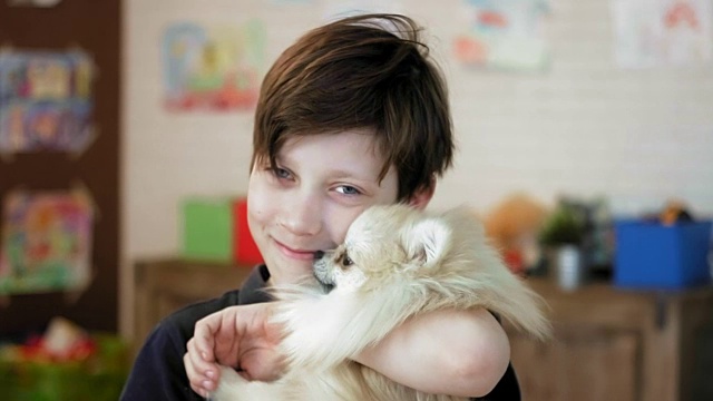 一个可爱的小男孩抱着他的小狗，微笑着看着镜头视频素材