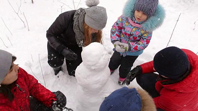 一家人带着孩子在公园里堆雪人。视频素材