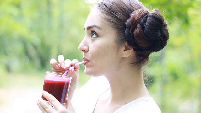 蔬菜排毒净化奶昔-女人通过吸管饮用。女孩喝红果汁。在户外。饮食和健康生活方式的概念视频素材