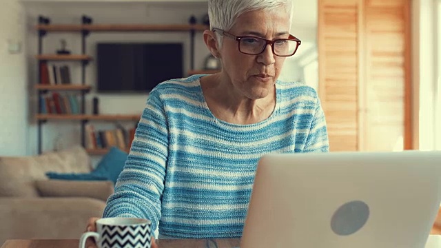 成熟的女人在笔记本电脑上写电子邮件，喝咖啡。视频素材