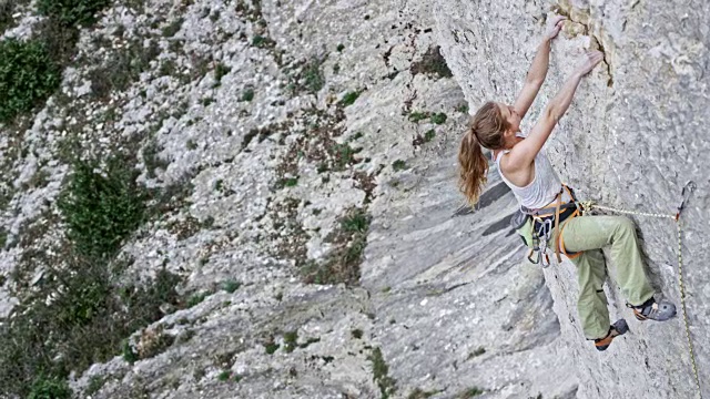 女攀岩者伸出手去抓住垂直的岩壁视频素材