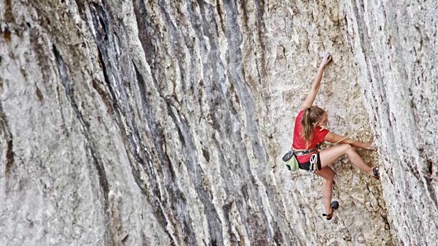 穿着红衬衫的女攀登者正在攀登悬崖视频素材
