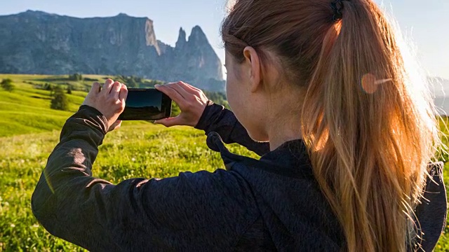 游客拍摄以山脉为背景的盛开的草地视频素材