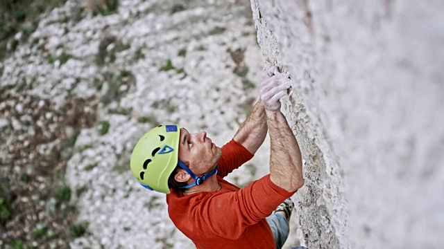 一名男性攀登者戴着一顶绿色头盔攀登悬崖视频素材
