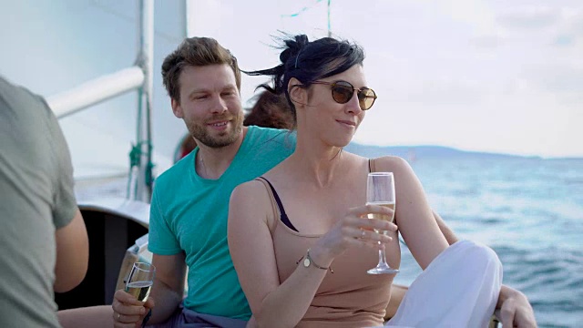 深褐色的女人和棕色头发的男人坐在游艇上，在夏日里喝着香槟视频下载