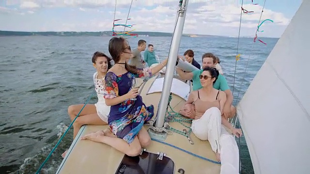 年轻人在海上划船，在有风的夏日喝香槟，坐在桅杆附近视频下载