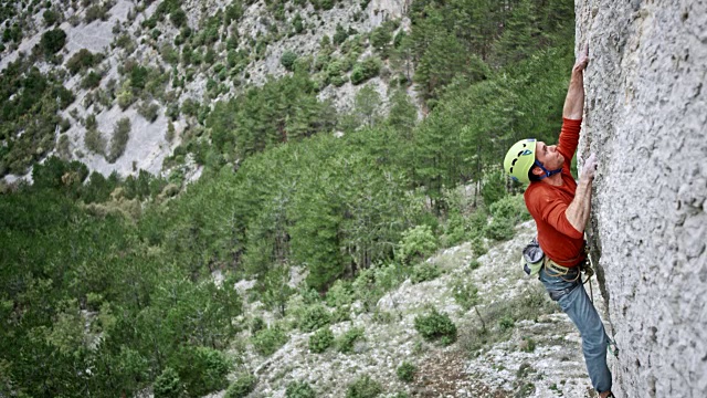 SLO MO一名男性登山者在悬崖的墙壁上找不到抓地力，只好松手视频下载