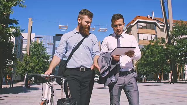 两名高管在城市中行走时使用数字平板电脑视频素材