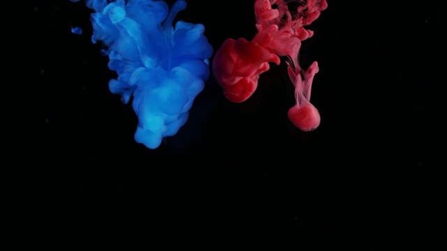 红色和蓝色墨水滴在水中黑色背景视频素材