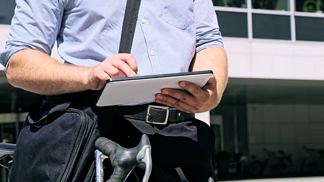 一名穿着衬衫的男子在办公大楼前使用数码平板电脑视频素材