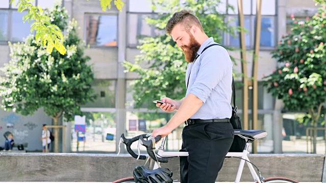 DS潮人用智能手机在城市里骑自行车视频素材