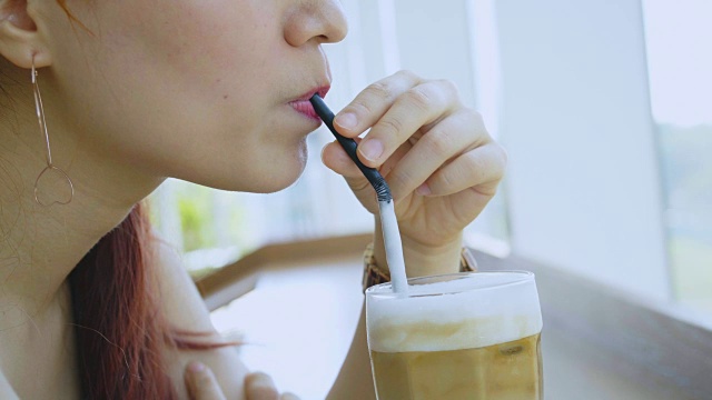 年轻的亚洲女士喝冰咖啡特写视频下载