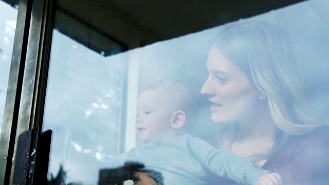 妈妈和她的孩子站在4k窗口附近视频素材