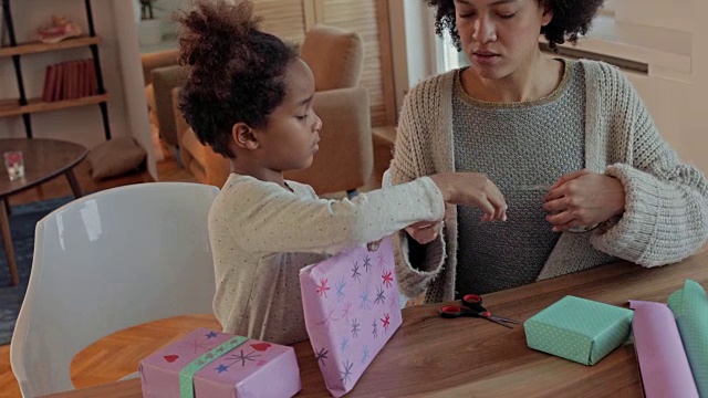 快乐的非裔美国母女在家里一起包装礼物。视频素材