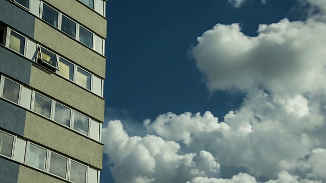 蓝天下的白云迅速掠过一栋四层住宅楼的特写视频下载