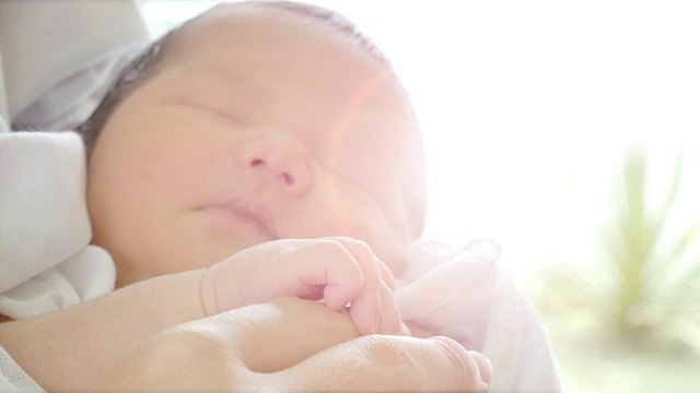父母的手抱着新生儿和婴儿在她的胳膊上睡觉的特写。幸福的家庭观念，渴望在没有喧闹的家中无忧无虑视频下载
