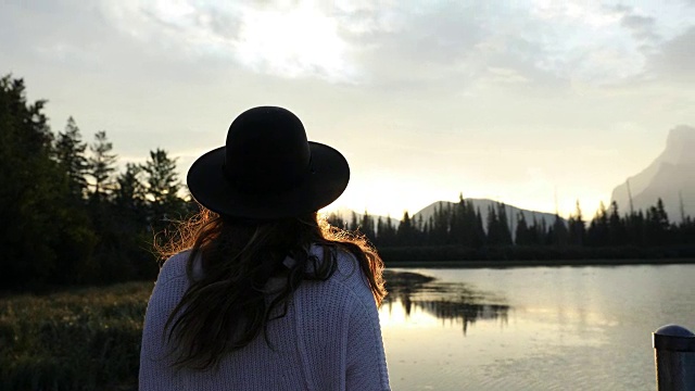 一位妇女在班夫国家公园的朱砂湖上看日出。视频素材