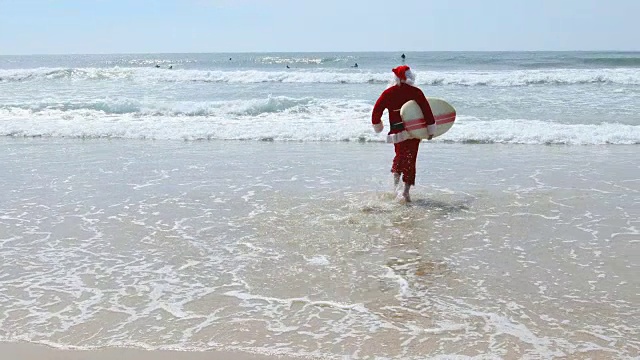 澳大利亚圣诞冲浪圣诞老人和冲浪板在海滩上跑步视频下载