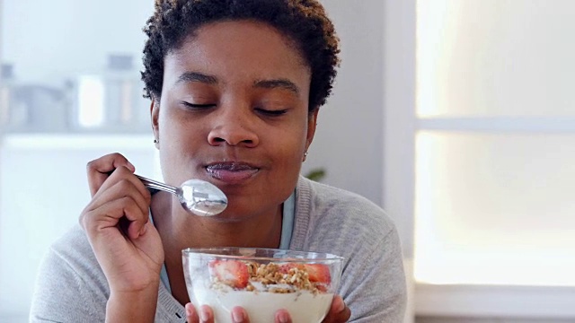 年轻的非洲裔美国妇女吃一碗健康的格兰诺拉麦片视频下载