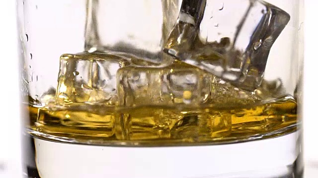用慢动作将威士忌倒入装有冰块的玻璃杯中视频素材