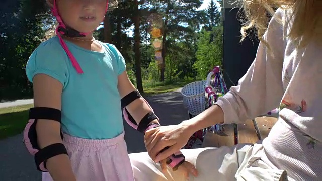 母亲帮助女儿戴护肘和手套视频素材