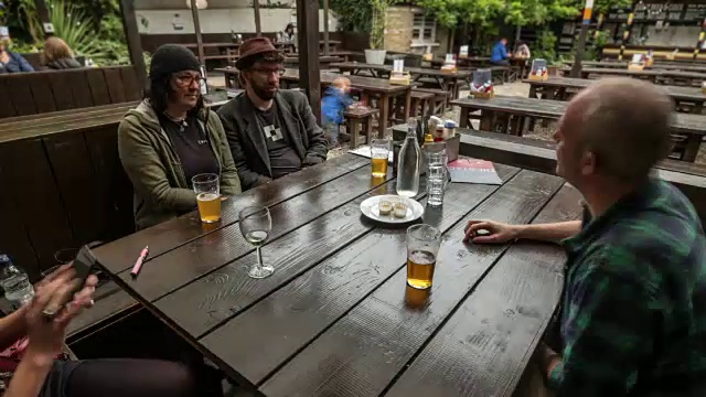 朋友们聚在一起喝酒，在当地的酒吧花园享受传统的周日烤肉视频素材