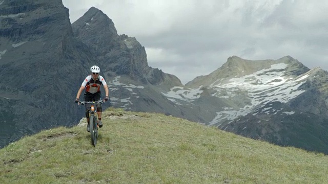 一个中年男子骑着他的山地车快速穿过高海拔的山道。视频素材