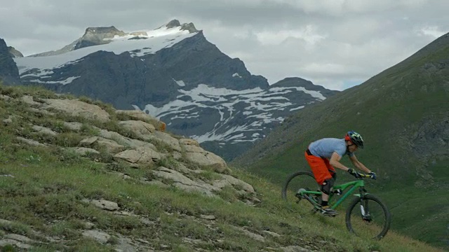 高山自行车在高冰川山脉岩石上缓慢移动。视频素材