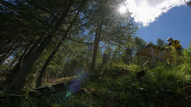 一个山下的山地自行车跳木在高山森林的缓慢动作。视频素材