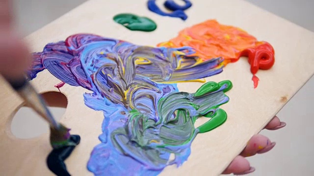 画家的手在调色板上混合鲜艳的颜色。4 k。视频素材