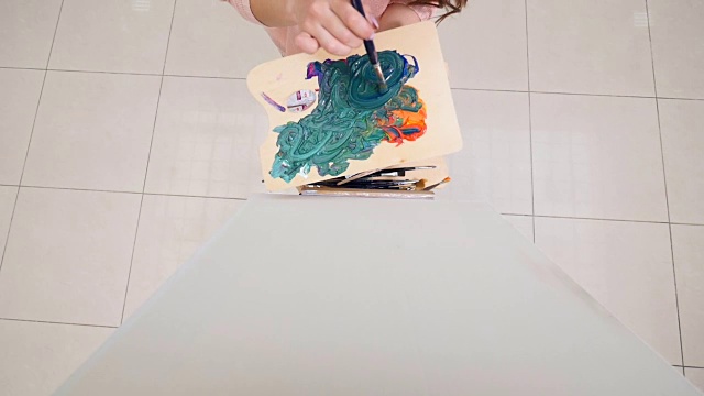 美丽的女人画家用油画颜料在白纸上画。4 k。视频素材