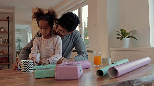 快乐的非裔美国父亲和女儿在家里包装礼物。视频素材