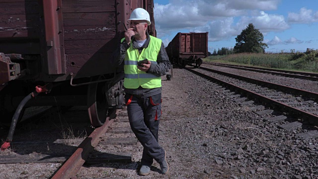 铁路员工在货车附近使用对讲机和平板电脑视频下载