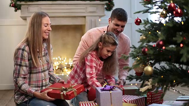 欢乐的家庭在圣诞树旁交换礼物视频素材