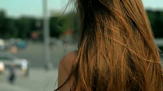 一个阳光明媚的日子里，年轻的黑发姑娘走在街上视频素材