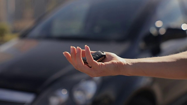 一个女人得到了一辆黑色汽车的新钥匙。视频素材