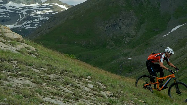 一个成熟的男性山地自行车手骑在岩石山景观。视频素材