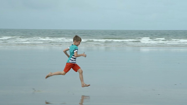 一个小男孩在海滩上跑步的时候看到的海洋。视频素材