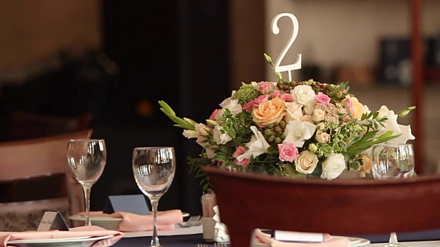 婚礼或生日时餐厅内部装饰的餐桌号码用白色和蓝色。在接待和宴会前，在咖啡馆的桌子上放上节日的植物或玫瑰视频下载