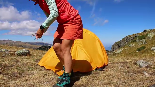 年轻迷人的女子在山上组装帐篷，假日户外露营营地视频下载